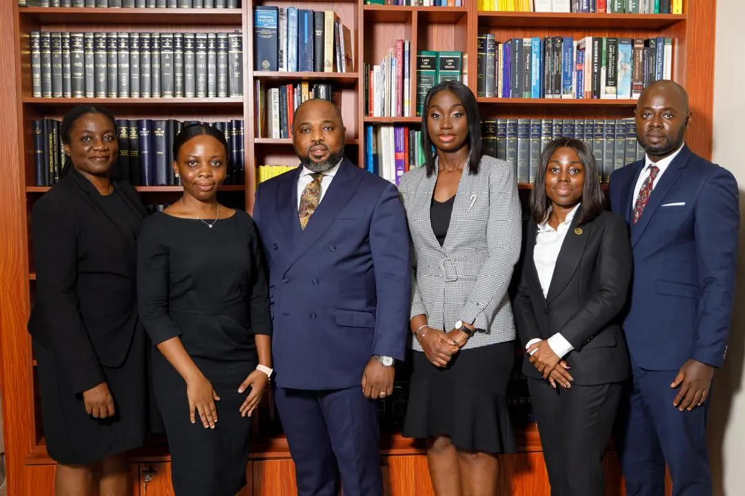 Six lawyers of MacCarthy & Associates standing together in front of the firm’s law library.