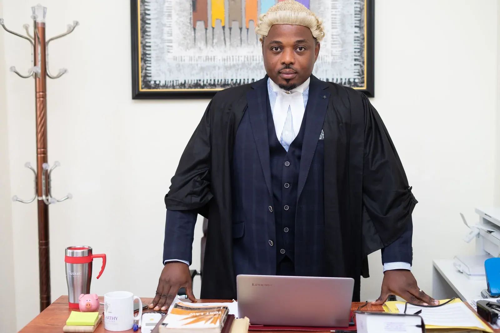 A barrister in wig and gown standing at his desk before leaving for court.