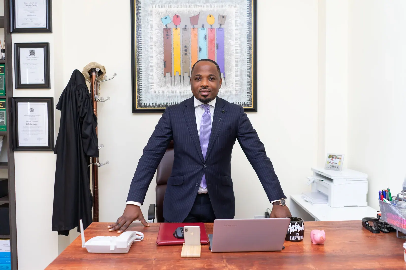 A lawyer in a dark suit standing at his desk in chambers.